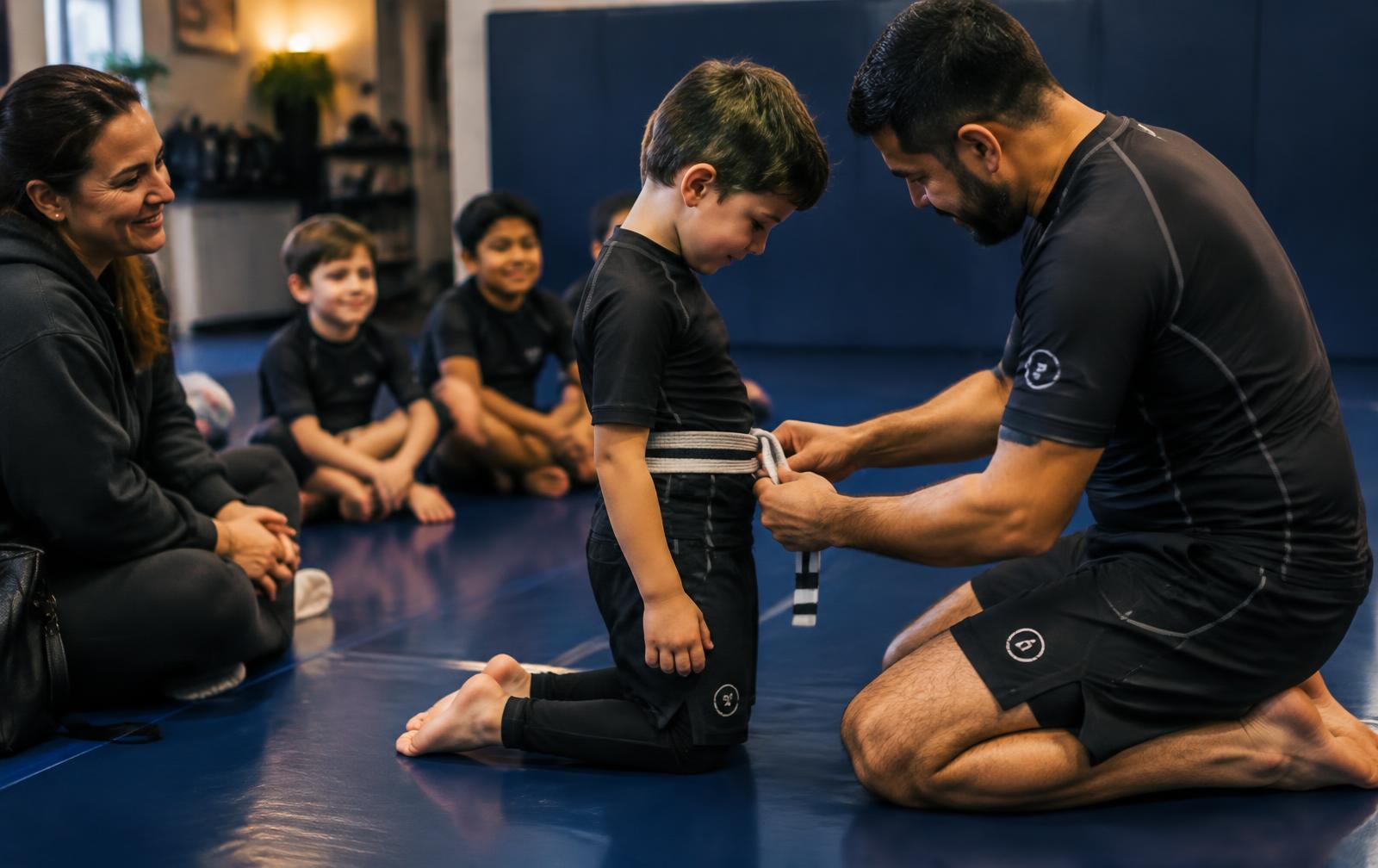 A coach tying a stripe belt on a young Jiu-Jitsu student